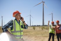 Smiling engineer talking on cell phone at sunny wind turbine power plant — Stock Photo