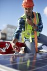 Male engineer with walkie-talkie repairing solar panel at power plant — Stock Photo