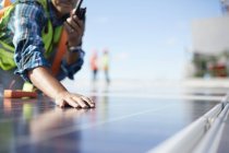 Инженер с рацией, осматривающий солнечные панели на электростанции — стоковое фото
