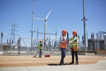 Engineers using digital tablet at sunny wind turbine power plant — Stock Photo