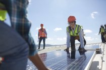 Ingenieros levantando panel solar en planta de energía soleada - foto de stock
