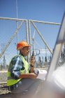 Engineer with walkie-talkie at sunny power plant — Stock Photo