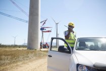 Engineer using walkie-talkie at truck at sunny wind turbine power plant — Stock Photo