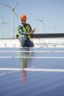 Engineer with equipment inspecting solar panels at sunny power plant — Stock Photo