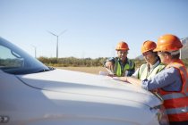 Ingenieros revisan proyecto en camión en planta de energía de turbina eólica soleada - foto de stock