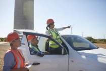 Engineers at truck at sunny wind turbine power plant — Stock Photo