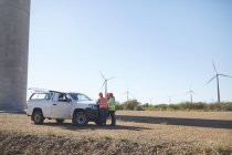 Інженери зустрічаються у вантажівці на сонячній вітрогенераторній електростанції — стокове фото