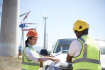 Ingenieure begutachten Baupläne bei LKW in sonnigem Windkraftwerk — Stockfoto