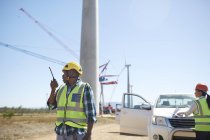 Engenheiro masculino com walkie-talkie na usina de turbina eólica ensolarada — Fotografia de Stock