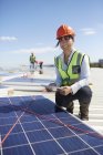 Porträt selbstbewusste, lächelnde Ingenieurin mit digitalem Tablet, die Sonnenkollektoren im Kraftwerk untersucht — Stockfoto