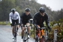 Cyclistes masculins dédiés cyclistes sur route pluvieuse — Photo de stock