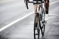 Велосипедист на мокрой дороге, крупный план — стоковое фото