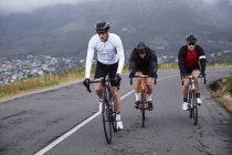 Dedicated male cyclists cycling on uphill road — Stock Photo