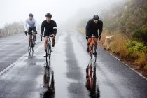 Cyclistes masculins sur route mouillée — Photo de stock