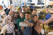 Entusiasta equipo creativo de negocios animando, tomando selfie en la oficina - foto de stock