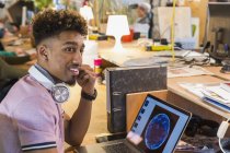 Креативний бізнесмен з навушниками, що працюють на ноутбуці в офісі — стокове фото