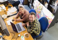 Porträt lächelnd, selbstbewusste kreative Geschäftsleute, die Müsli essen, im Büro am Laptop arbeiten — Stockfoto