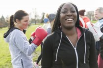Retrato sonriente, mujer segura boxeando en el parque con amigos - foto de stock