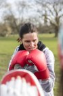 Femme ciblée et déterminée boxe dans un parc vert — Photo de stock