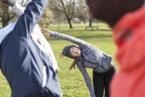 Woman exercising, stretching in green park — Stock Photo