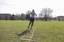 Femme faisant de l'exercice, faisant des exercices d'échelle de vitesse dans un parc ensoleillé — Photo de stock