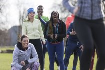 Team cheering woman exercising in park — Stock Photo