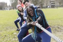 Determined team pulling rope in tug-of-war at park — Stock Photo