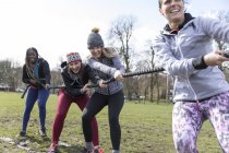 Determined women pulling rope in tug-of-war in sunny park — Stock Photo