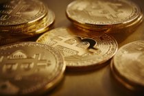 Goldene Bitcoins auf goldener Oberfläche verstreut — Stockfoto