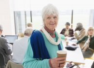 Портрет впевнена старша бізнес-леді п'є каву на зустрічі — стокове фото
