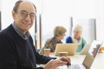 Улыбающийся портрет, уверенный старший бизнесмен, использующий ноутбук в конференц-зале — стоковое фото
