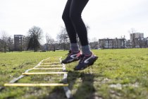 Cropped image of woman using exercising ladder in park — Stock Photo
