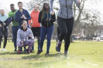 Team cheering woman doing speed ladder drill in sunny park — Stock Photo