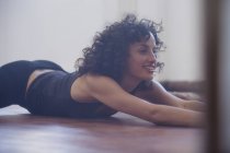 Усміхаючись, впевнена молода танцівниця розтягується в танцювальній студії — стокове фото