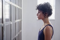 Профіль серйозна молода танцівниця, що стоїть у дзеркалі в танцювальній студії — стокове фото