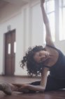 Изящная молодая танцовщица, растянувшаяся в танцевальной студии — стоковое фото