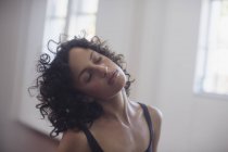 Спокойная молодая танцовщица, растягивающая шею в танцевальной студии — стоковое фото