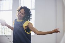 Unbekümmerte junge Tänzerin hört Musik mit Kopfhörer und mp3-Player — Stockfoto