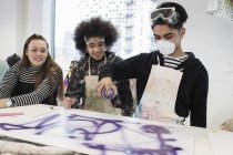 Teenagers spray painting in art class — Stock Photo