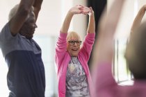Smiling active seniors exercising, stretching arms — Stock Photo