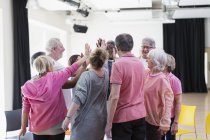Active seniors high-fiving in circle huddle — Stock Photo
