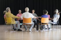 Active seniors meditating, holding hands in circle — Stock Photo