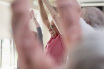 Lächelnder aktiver Senior streckt Arme in Turnstunde über Kopf — Stockfoto