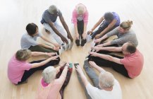 Anziani attivi che allungano gambe in cerchio in classe di esercizio — Foto stock
