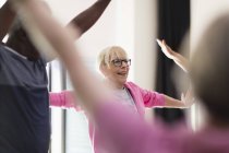 Sorrindo ativa mulher idosa esticando os braços em classe de exercício — Fotografia de Stock
