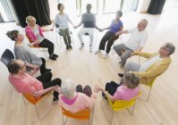 Active seniors holding hands in circle, meditating in community center — Stock Photo