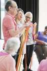 Smiling active seniors and instructor stretching, exercising with straps — Stock Photo