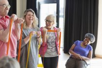 Happy instructor and active seniors exercising with straps — Stock Photo