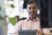Усміхнений бізнесмен працює на цифровому планшеті в офісі — стокове фото