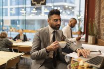 Сфокусированный бизнесмен пьет кофе и работает за ноутбуком в кафе — стоковое фото